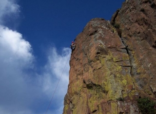 hombre escalando la cima de una montana